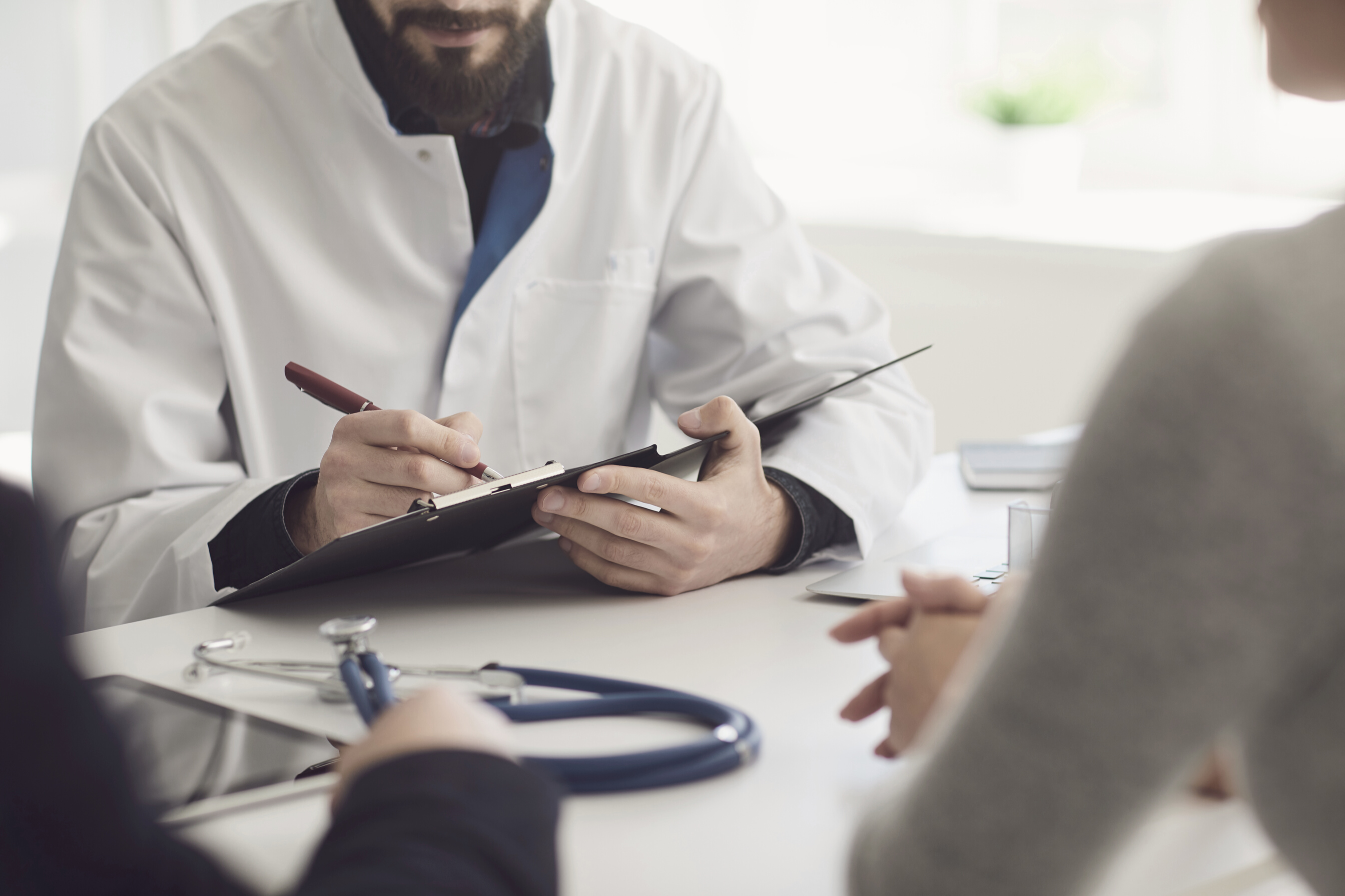 Confident Doctor and Couple Patient Sitting at the Table in Clinic Office. Family Doctor. Faceless.